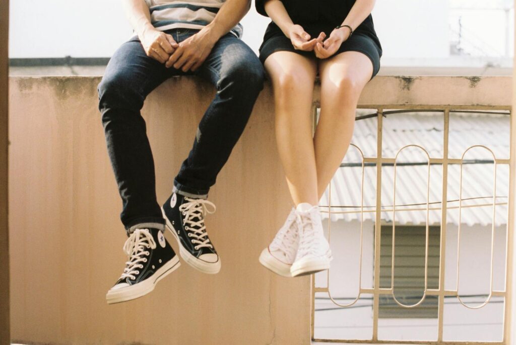 A relaxed couple sitting on a ledge, wearing stylish sneakers, showcasing togetherness.