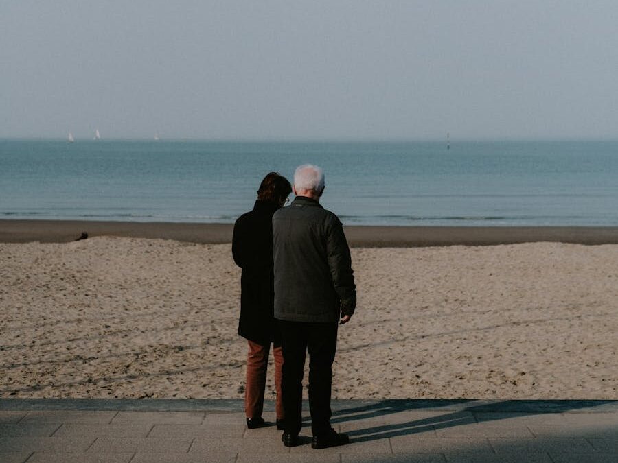Two people enjoying a peaceful moment at the beach, gazing at the calm sea.