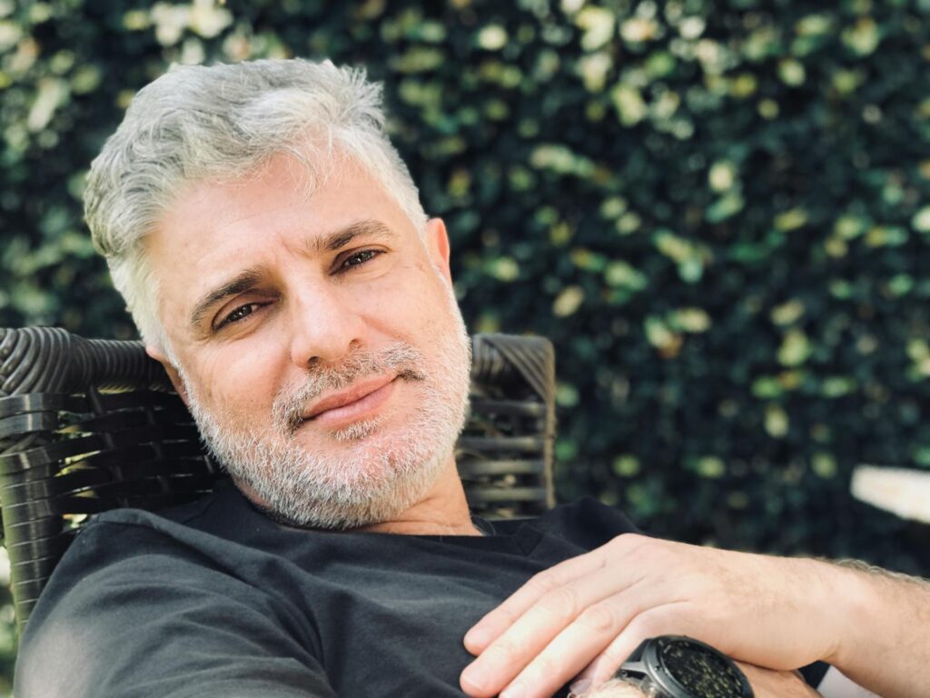 Close portrait of a relaxed adult man with gray hair reclining outdoors.