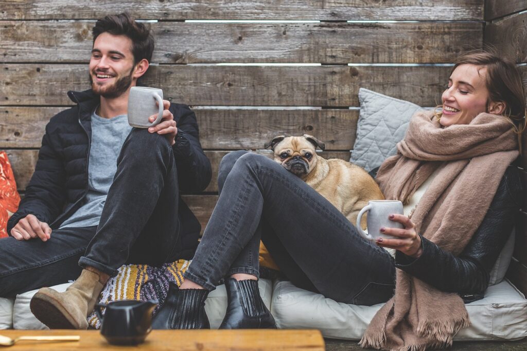 merry christmas, man, woman, dog, pet, pug, owners, couple, relationship, warm clothes, cozy, scarf, jackets, jeans, boots, fashion, people, happy, love, female, young, male, adult, caucasian, happiness, romantic, portrait, smile, smiling, girlfriend, date, boyfriend, together, person, lovers, sitting, relaxing, rustic, cushions, couch, animal, laughing, enjoying, coffee