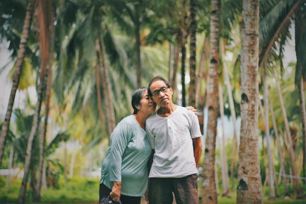 Elderly couple shares a tender moment in a lush tropical setting, symbolizing timeless love.