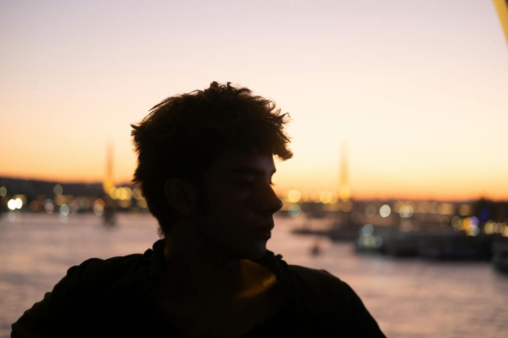Silhouette of a man at sunset with Istanbul skyline in the background, featuring vibrant city lights.