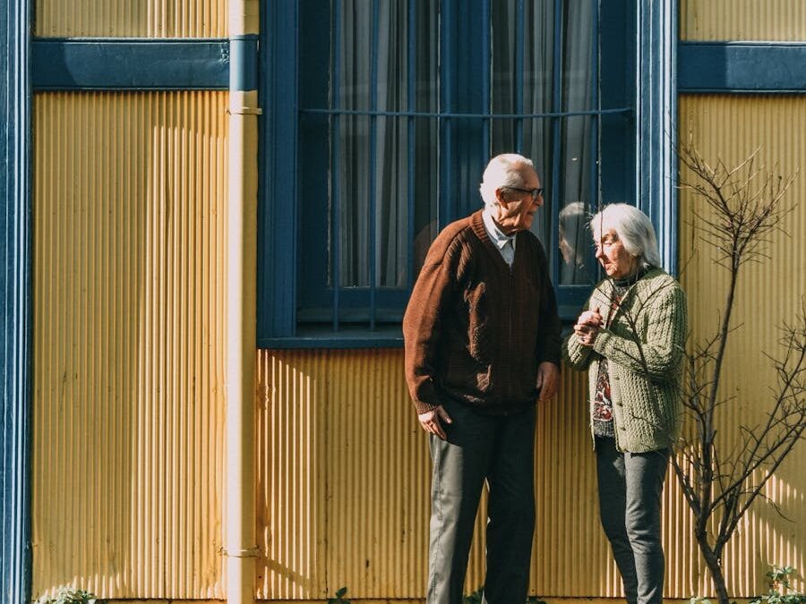 A senior couple standing in front of a colorful building in Valparaíso, enjoying the sunny day.