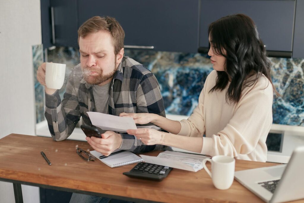 Couple discussing financial documents and budgeting at a kitchen table.