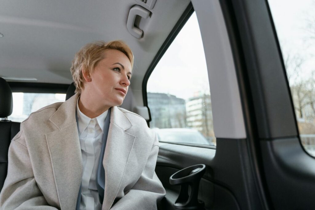 Businesswoman in a car, gazing thoughtfully out the window during a business trip.