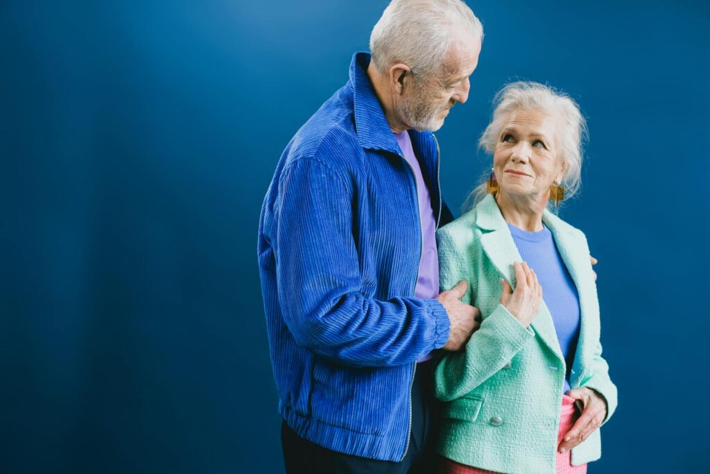 Charming elderly couple sharing a loving moment. Indoor studio setting with vibrant blue backdrop.
