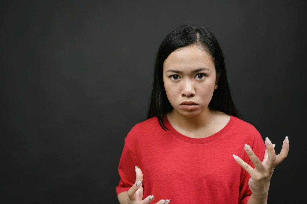 A young woman with expressive hands showing emotions against a dark background.