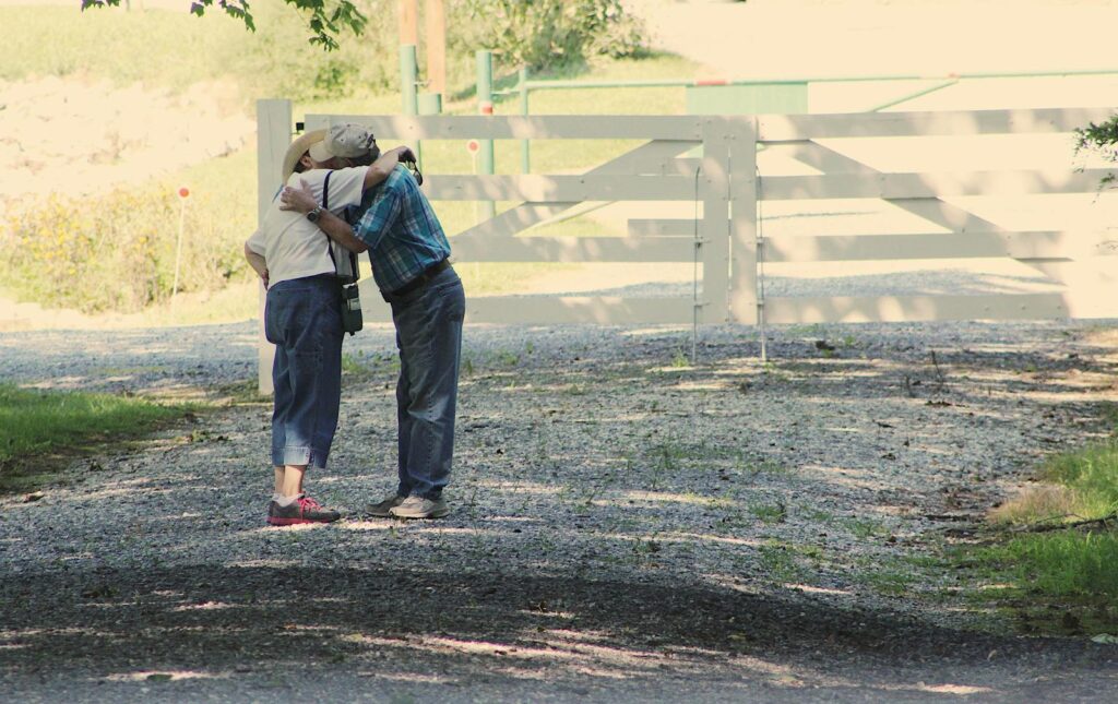 Two seniors embracing on a sunny day in a serene park.