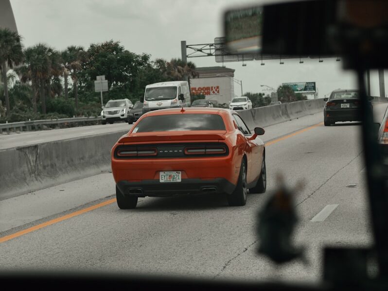 a red car driving down a highway next to a bridge