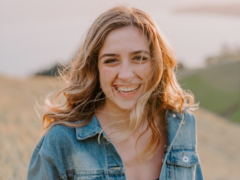 smiling woman sitting on grass during daytime