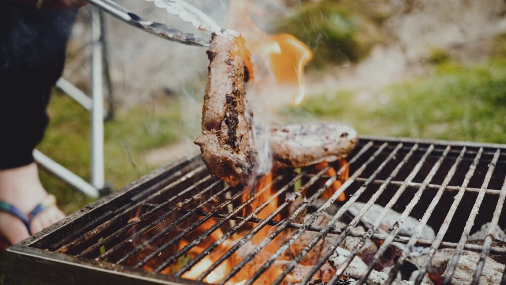 a person is grilling some meat on a grill