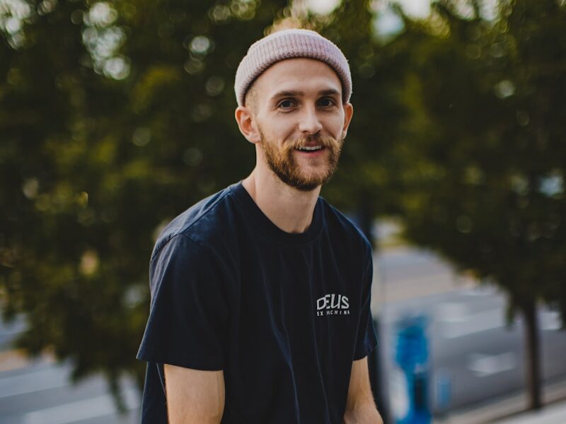 man in black crew neck t-shirt and blue denim jeans sitting on gray concrete bench