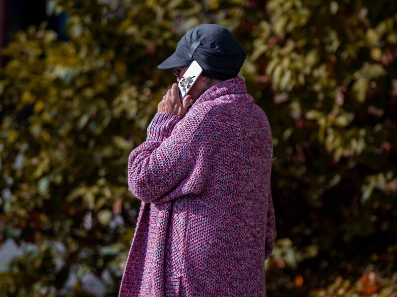 a woman in a purple coat talking on a cell phone