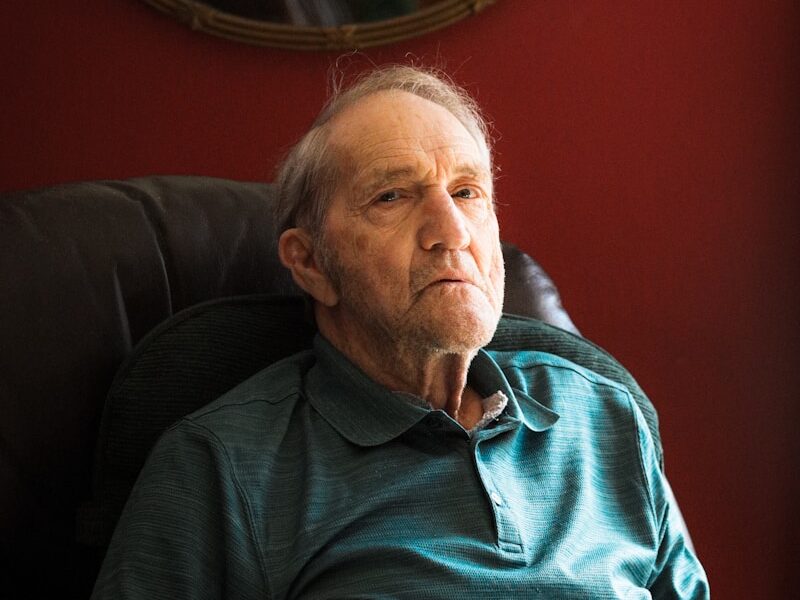 man in blue sweater sitting on black sofa