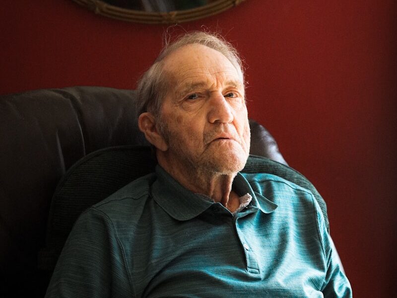 man in blue sweater sitting on black sofa
