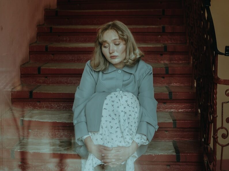 girl in pink long sleeve shirt and white skirt sitting on brown wooden staircase