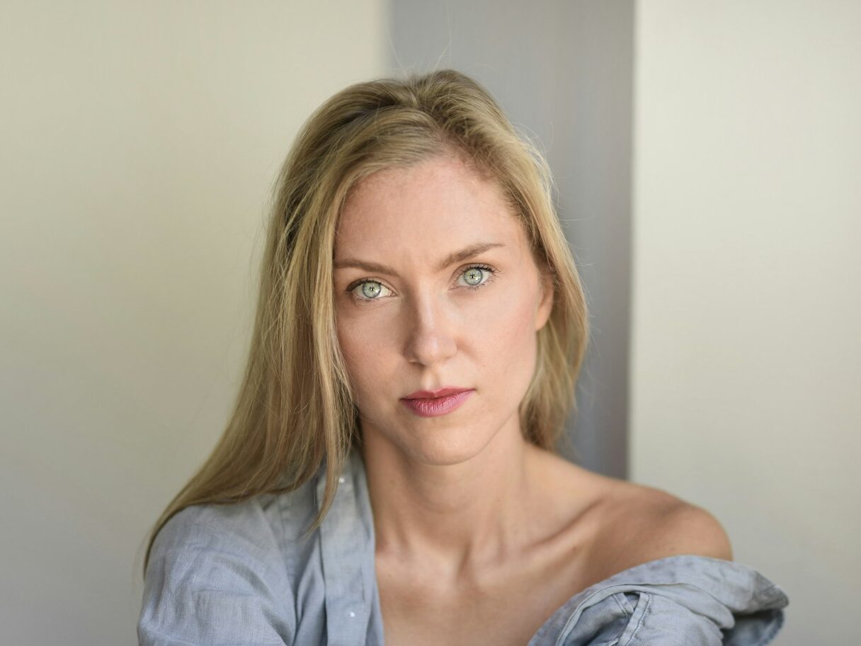 woman wearing blue button-up long-sleeved shirt near white surface