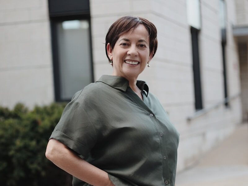 man in green button up t-shirt and white pants standing on road during daytime