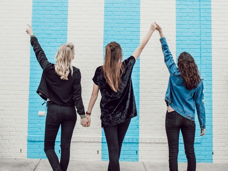 three woman holding hands white walking