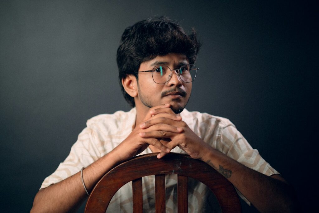 a man sitting at a wooden chair with his hands folded