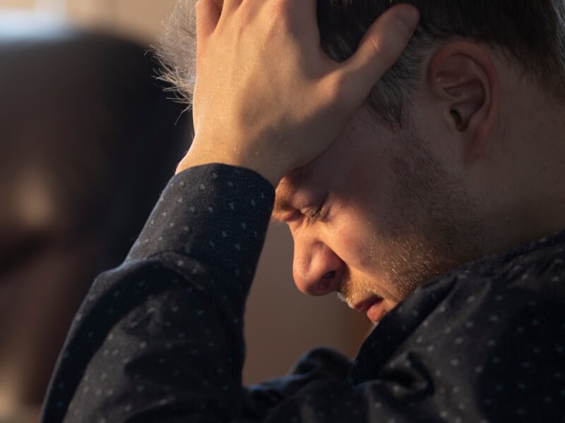 a man sitting at a table with his hand on his head