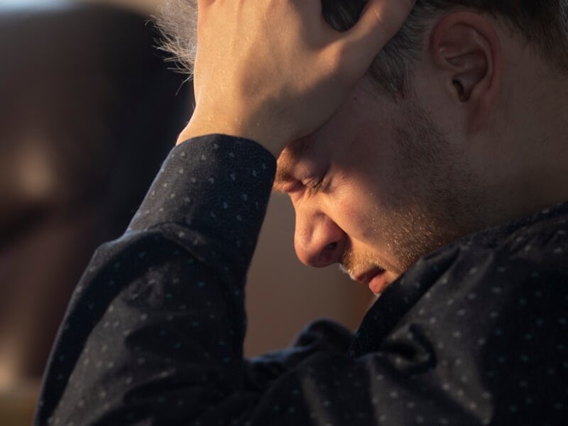 a man sitting at a table with his hand on his head