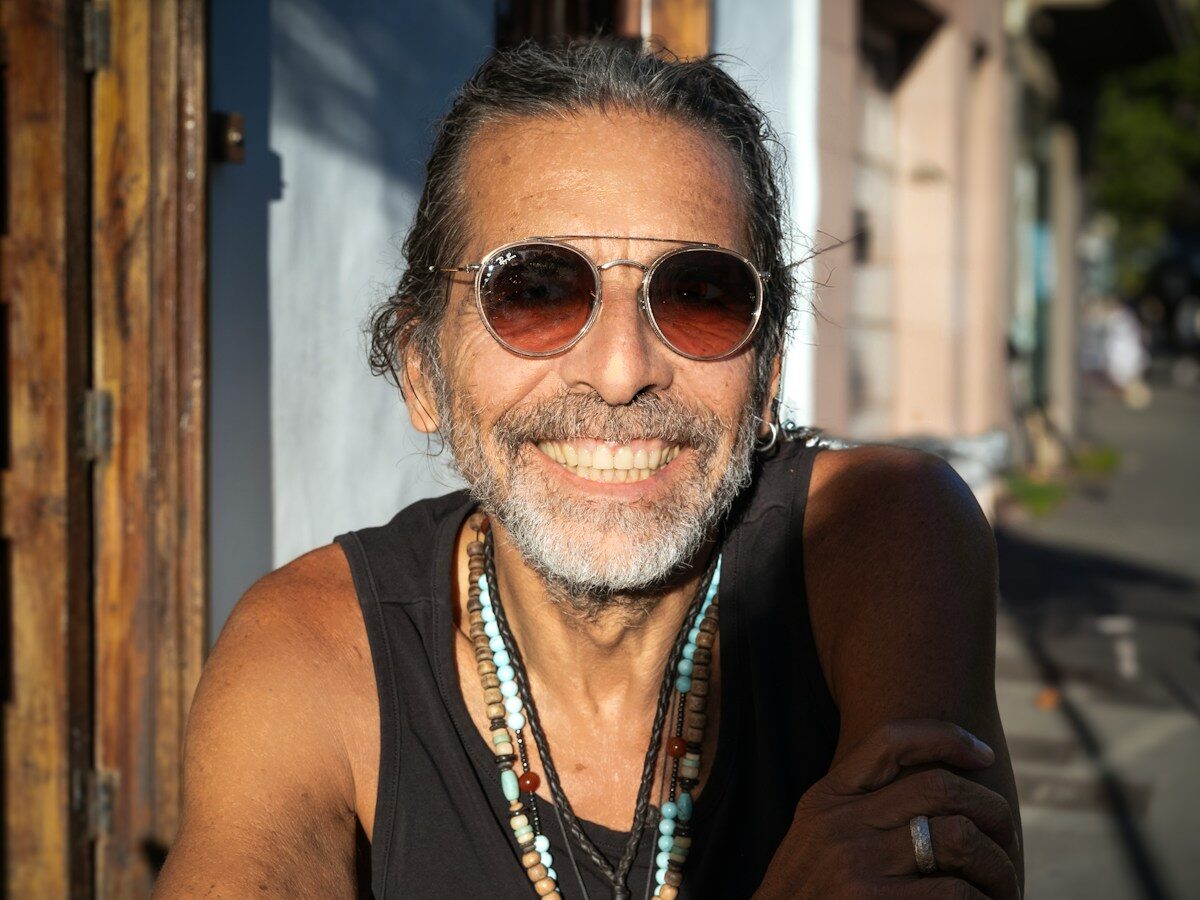 a man wearing sunglasses and a beaded necklace