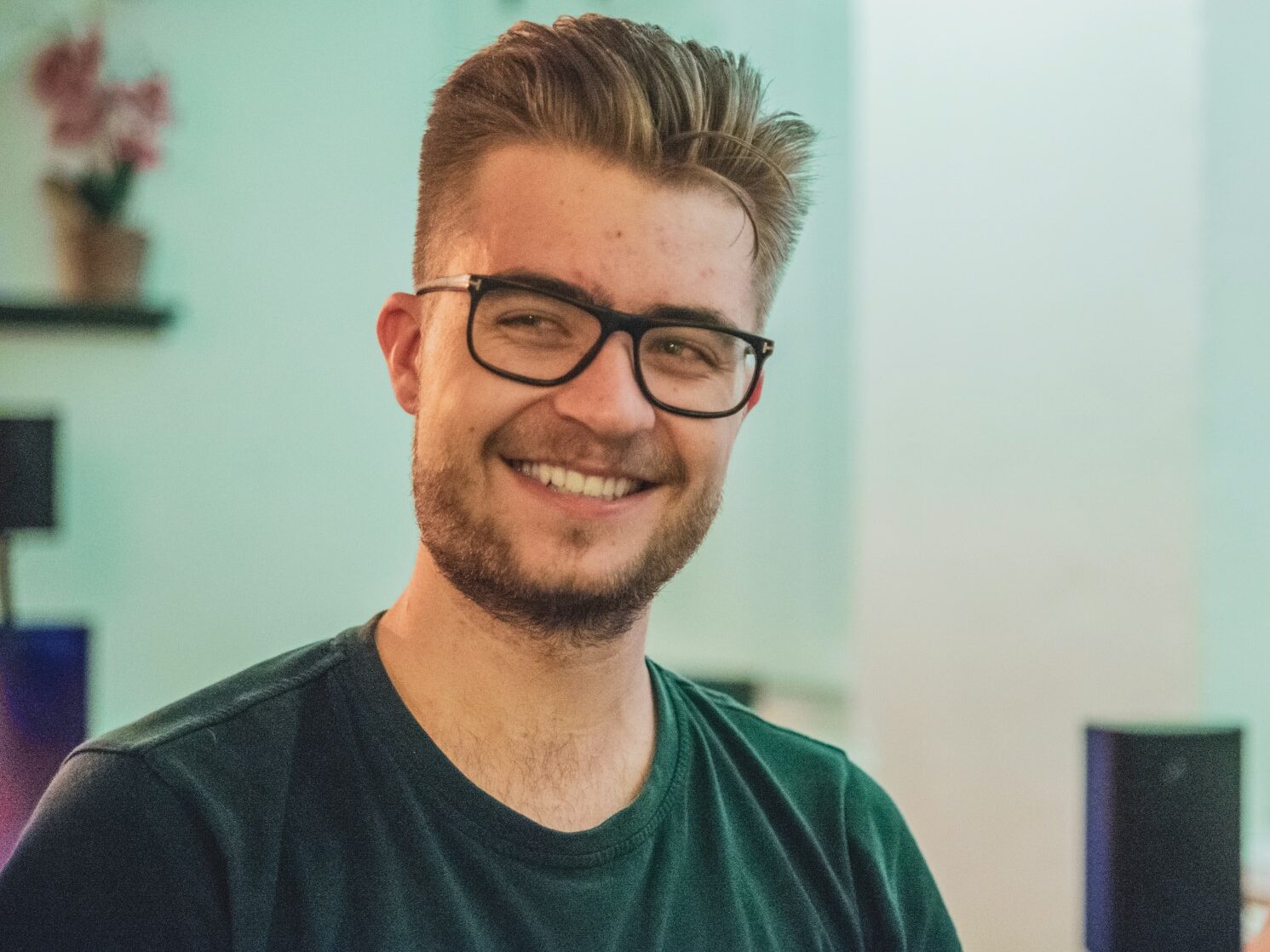 man wearing green crew-neck top and eyeglasses with black frames looking at side