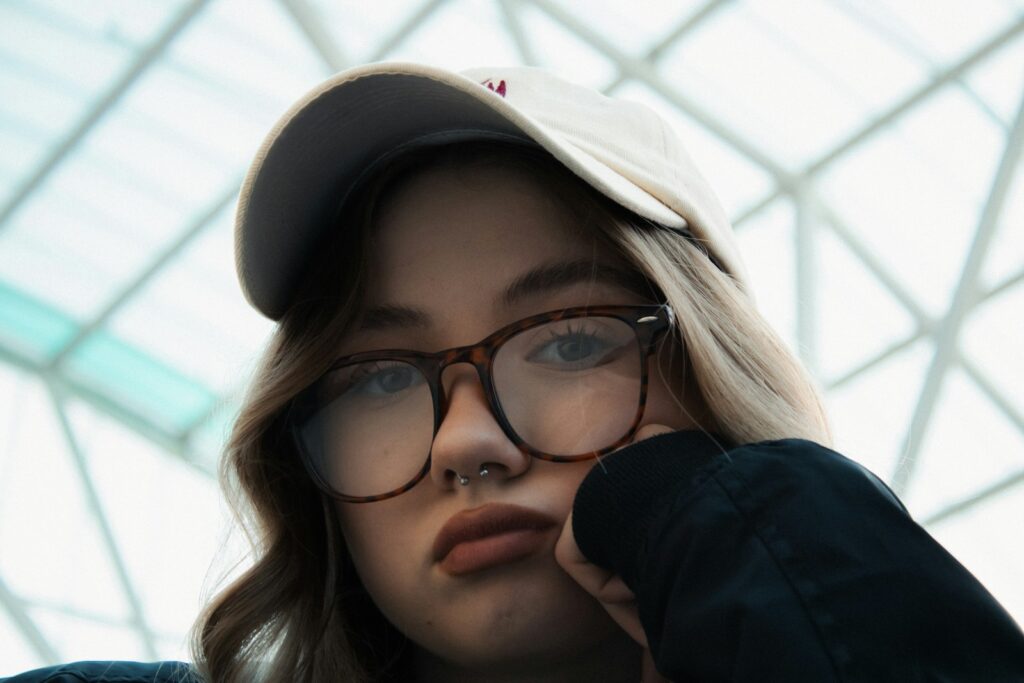 Young woman wearing glasses and a hat.