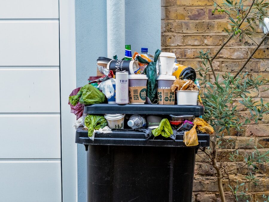 black trash bin with green leaves