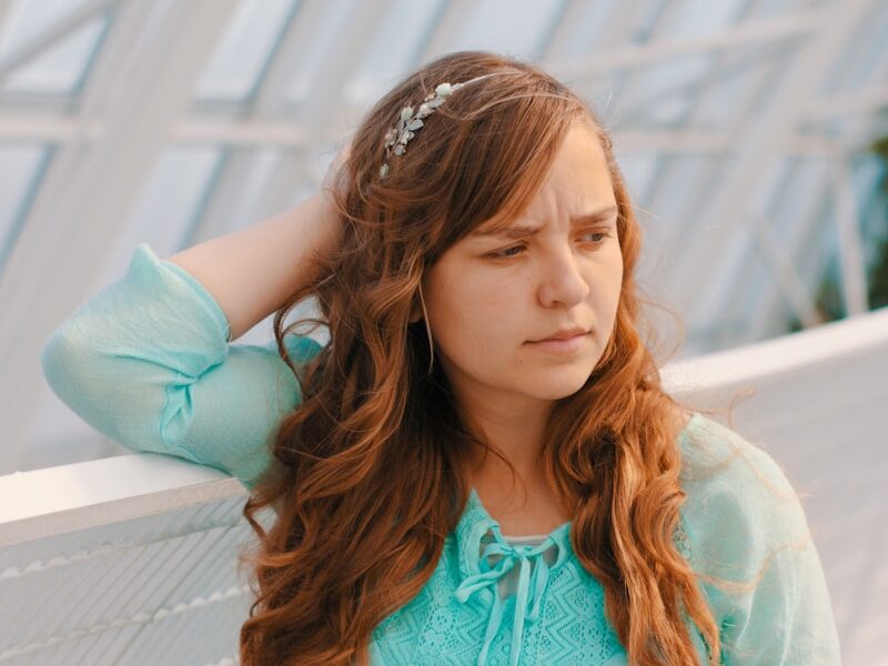 woman holding head near white handrail