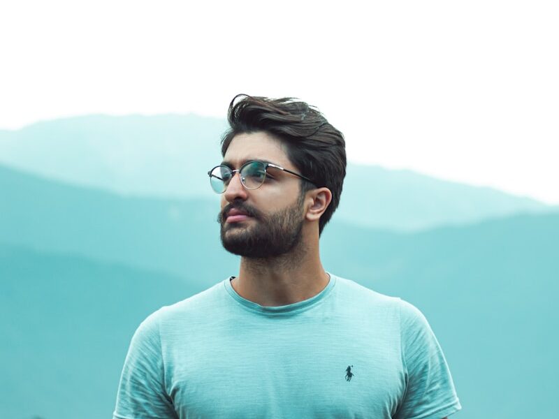 man in teal crew neck shirt wearing black framed eyeglasses