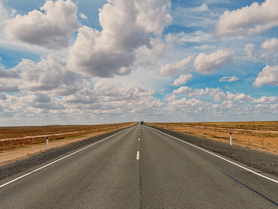 a long empty road with a sky filled with clouds