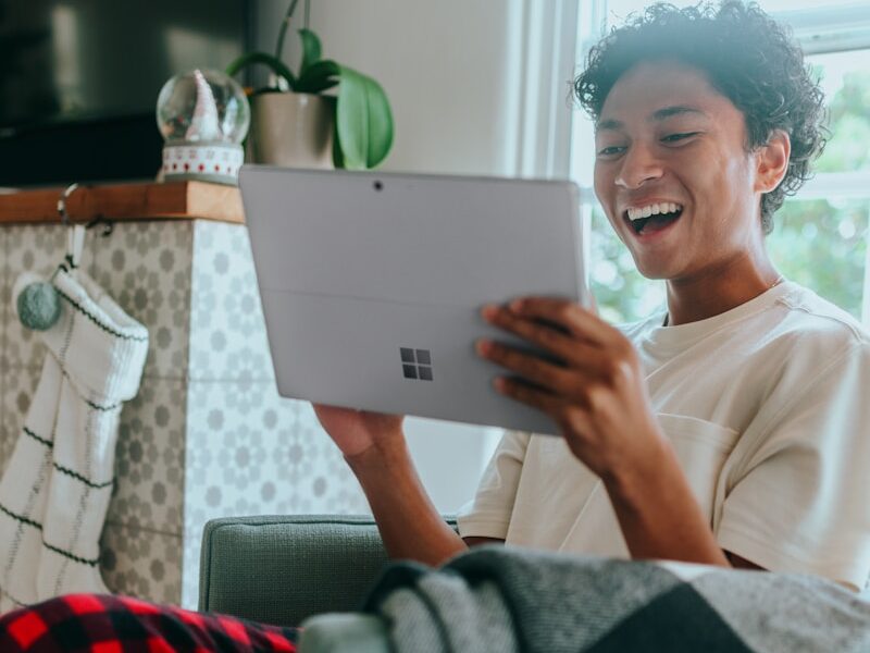 Man at home wearing pyjamas smiling at Surface Laptop screen