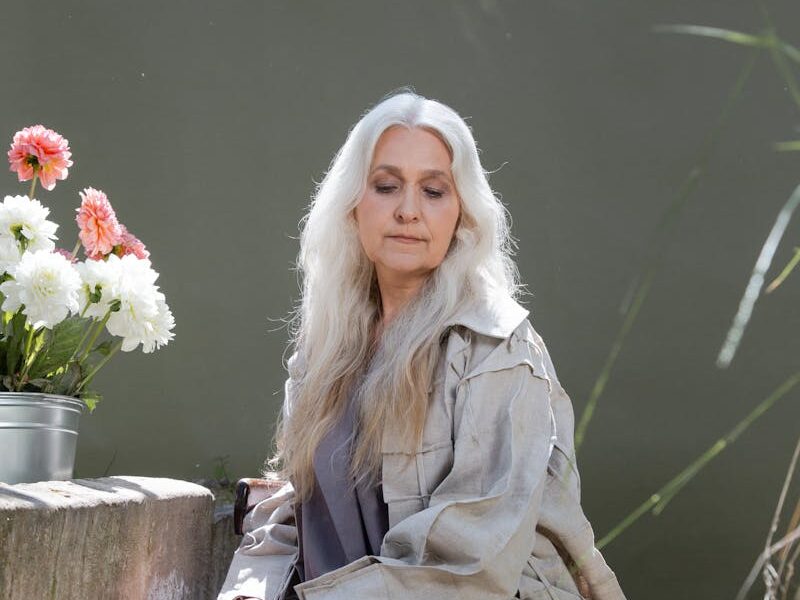Elegant senior woman among colorful flowers, exuding grace and tranquility in a garden setting.