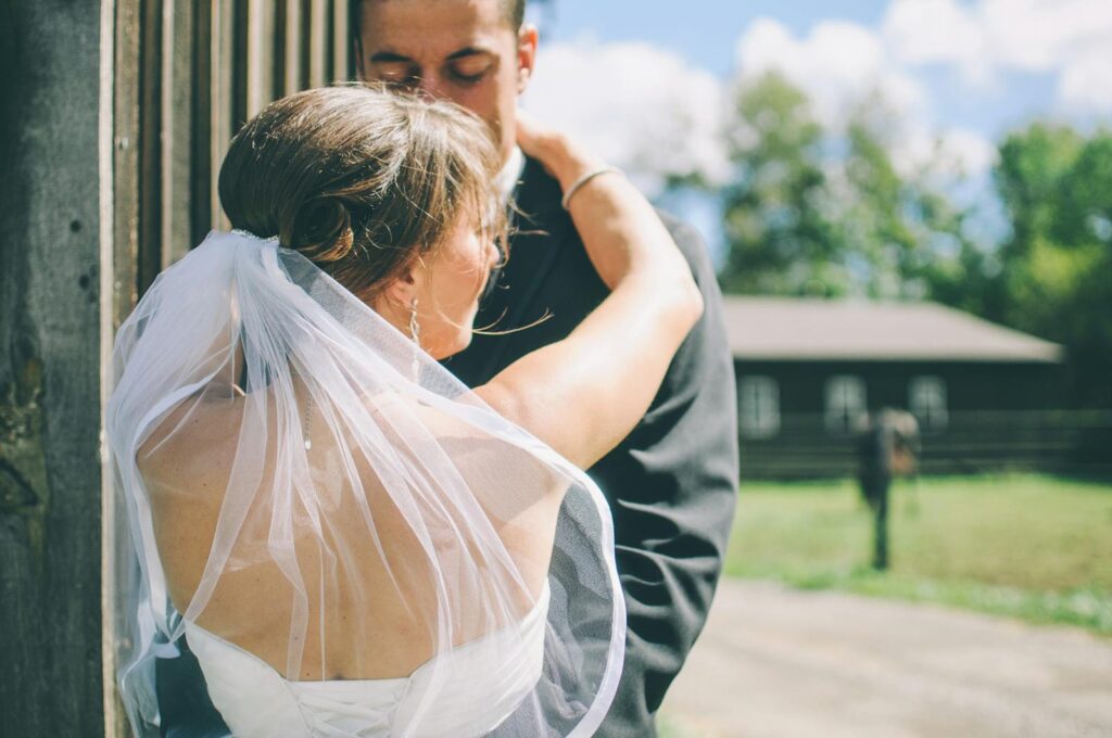 A bride and groom embracing outdoors on a sunny day, capturing love and romance.