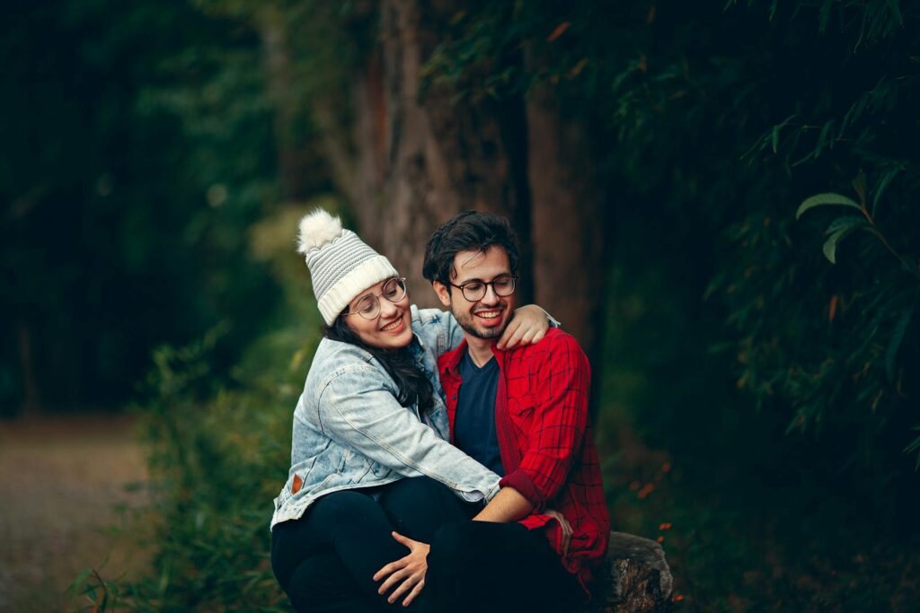 Happy couple sitting together in a green park, enjoying a joyful moment filled with love and affection.