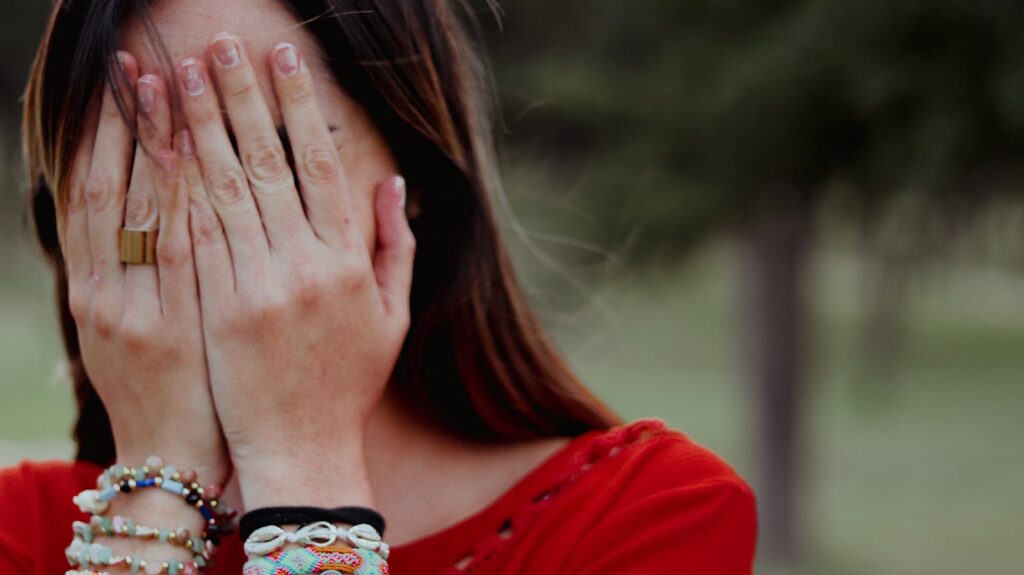 Woman covering her face with hands in an emotional moment outdoors.