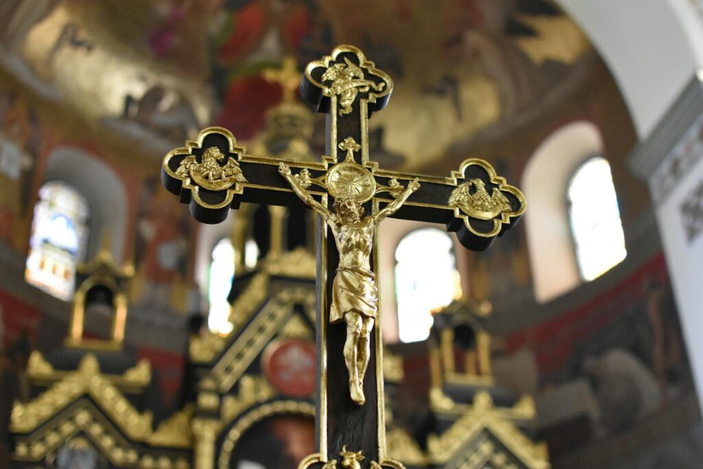 Close-up of a detailed gold crucifix in an elaborate church interior, symbolizing Christian faith and spirituality.