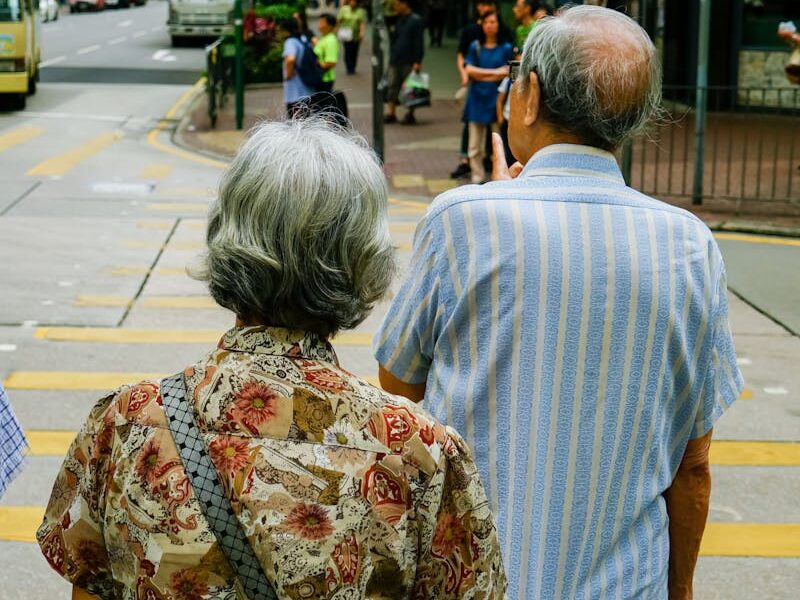 Senior couple waiting at a crosswalk in urban Kowloon, Hong Kong, during the day.