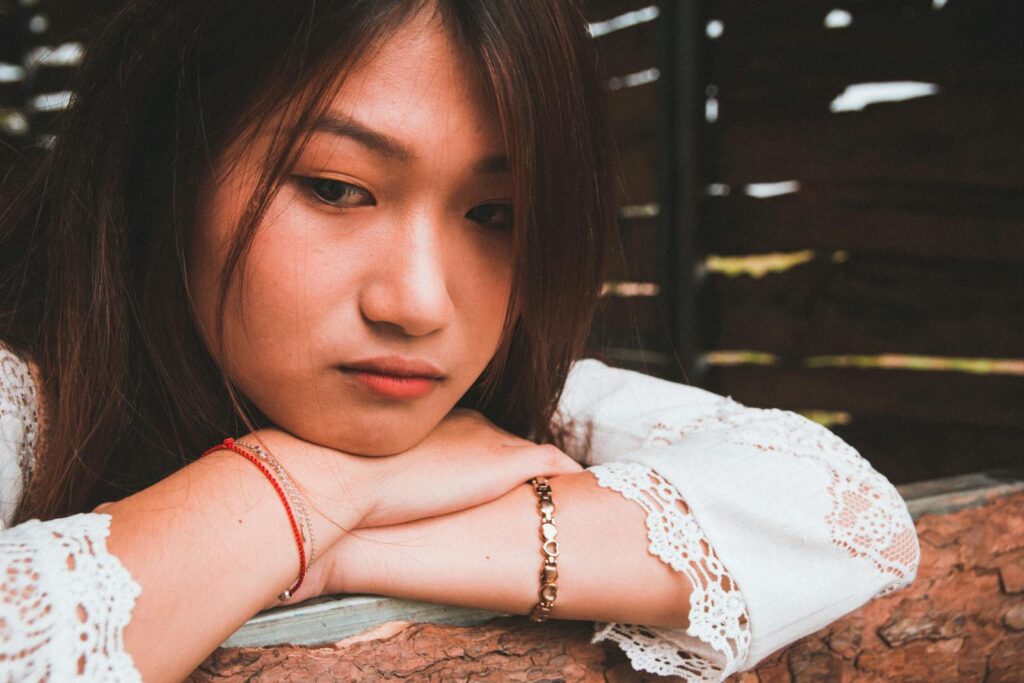 Thoughtful young woman resting her chin on a tree branch, deep in contemplation.