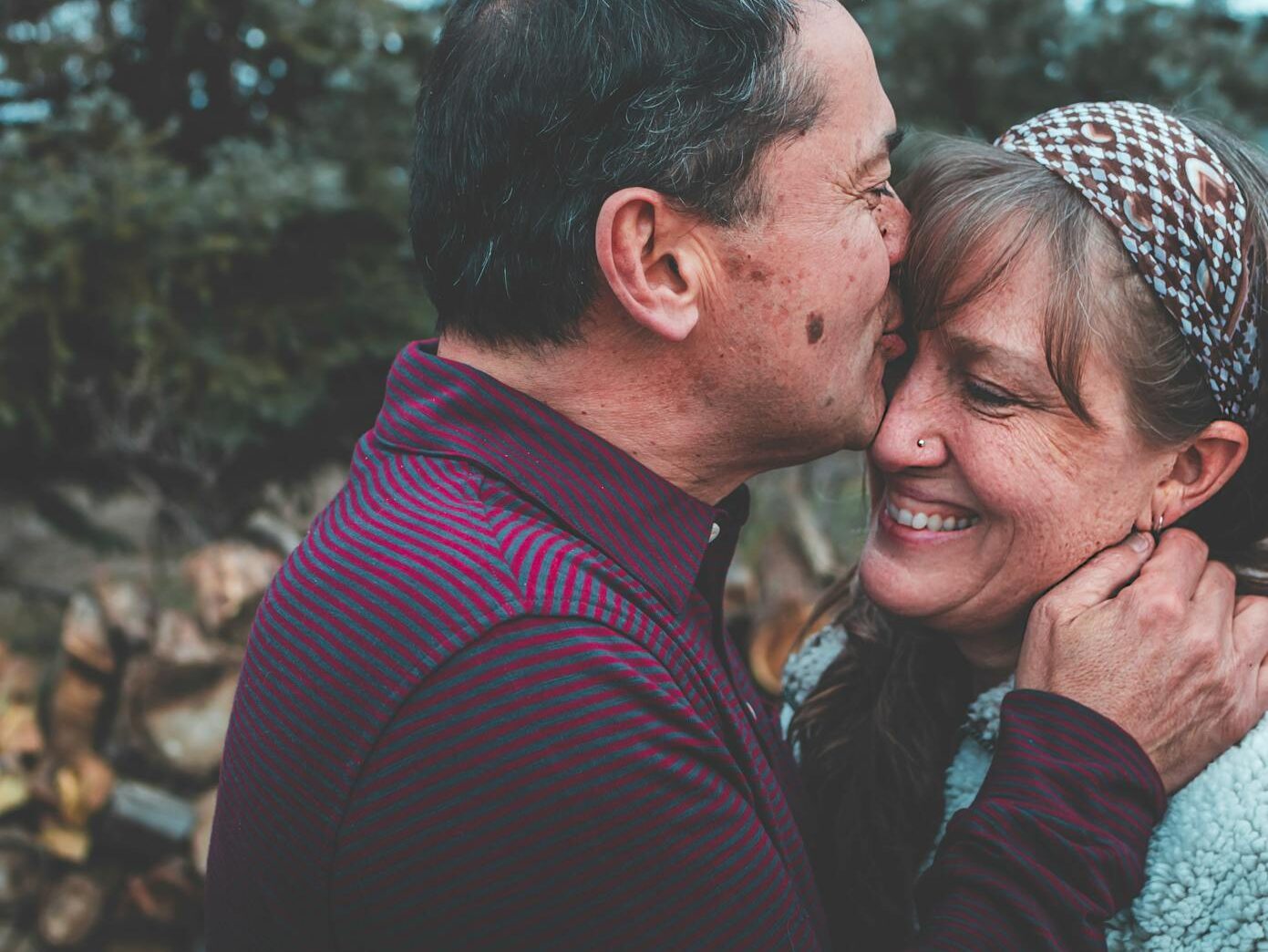 A loving couple shares a tender moment outdoors in a garden setting, expressing happiness and affection.
