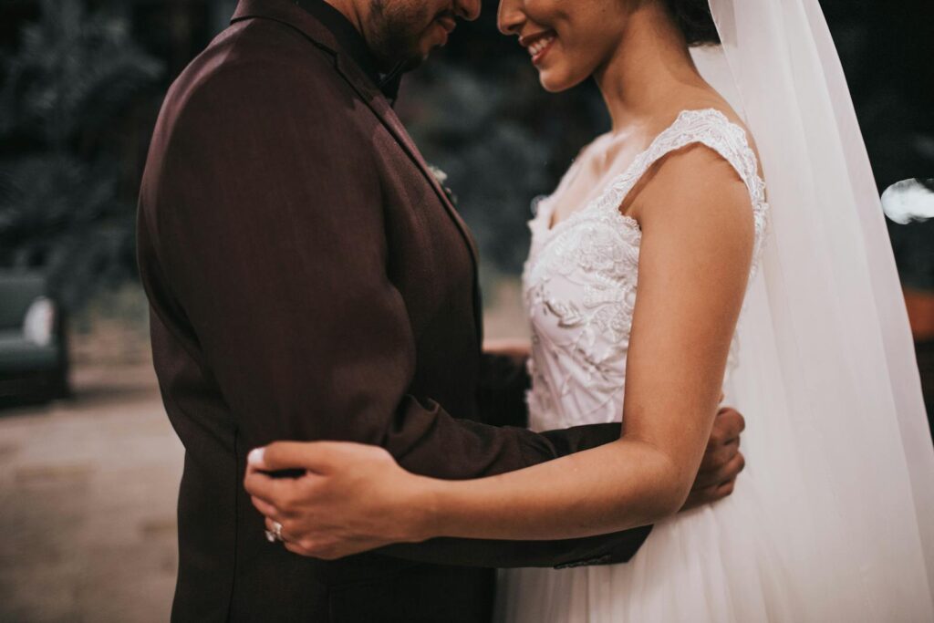 A bride and groom share a romantic embrace during their wedding. Captured in a warm, intimate setting.