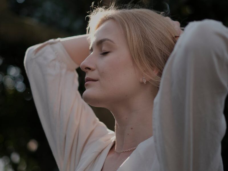 A woman is standing in front of a tree and looking up