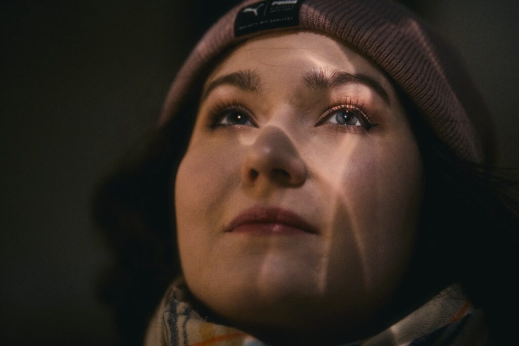 A woman wearing a hat and scarf looking up