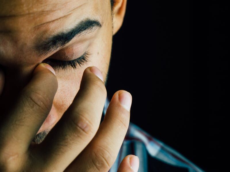 A close-up portrait capturing the emotional expression of a man in a dark studio setting.