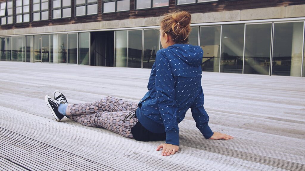 A teenager sits casually on a wooden deck, embodying modern urban style and leisure.