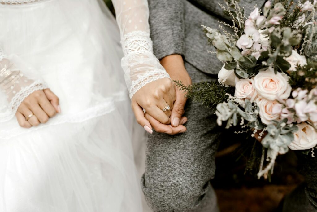Close-up of a couple holding hands with a floral bouquet, symbolizing romance and togetherness.