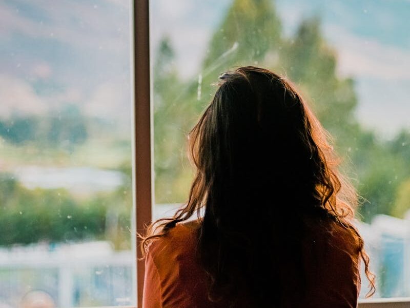 Silhouette of a woman looking out a window at a scenic mountain view in Cajamarca, Peru.