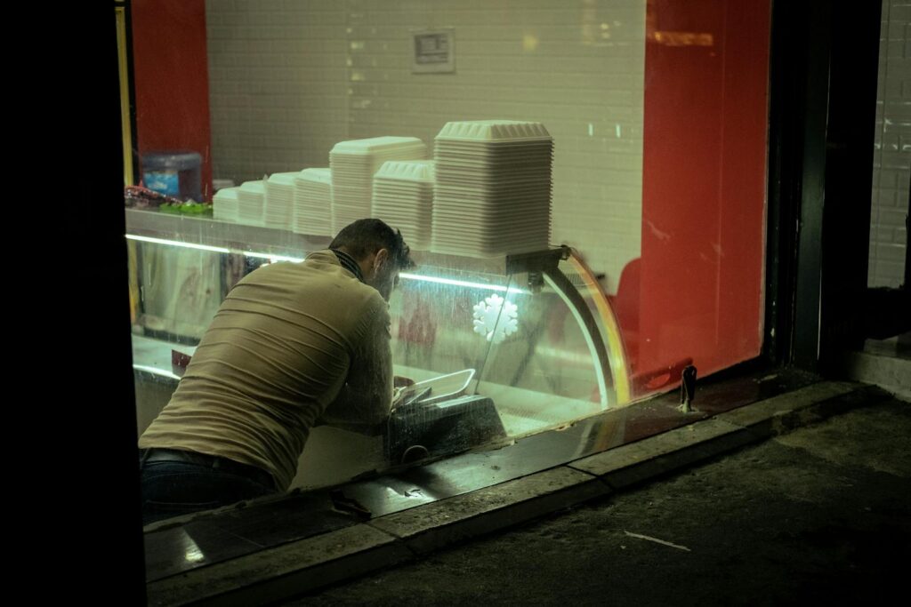 A man arranging containers in a takeaway restaurant, seen through a window.